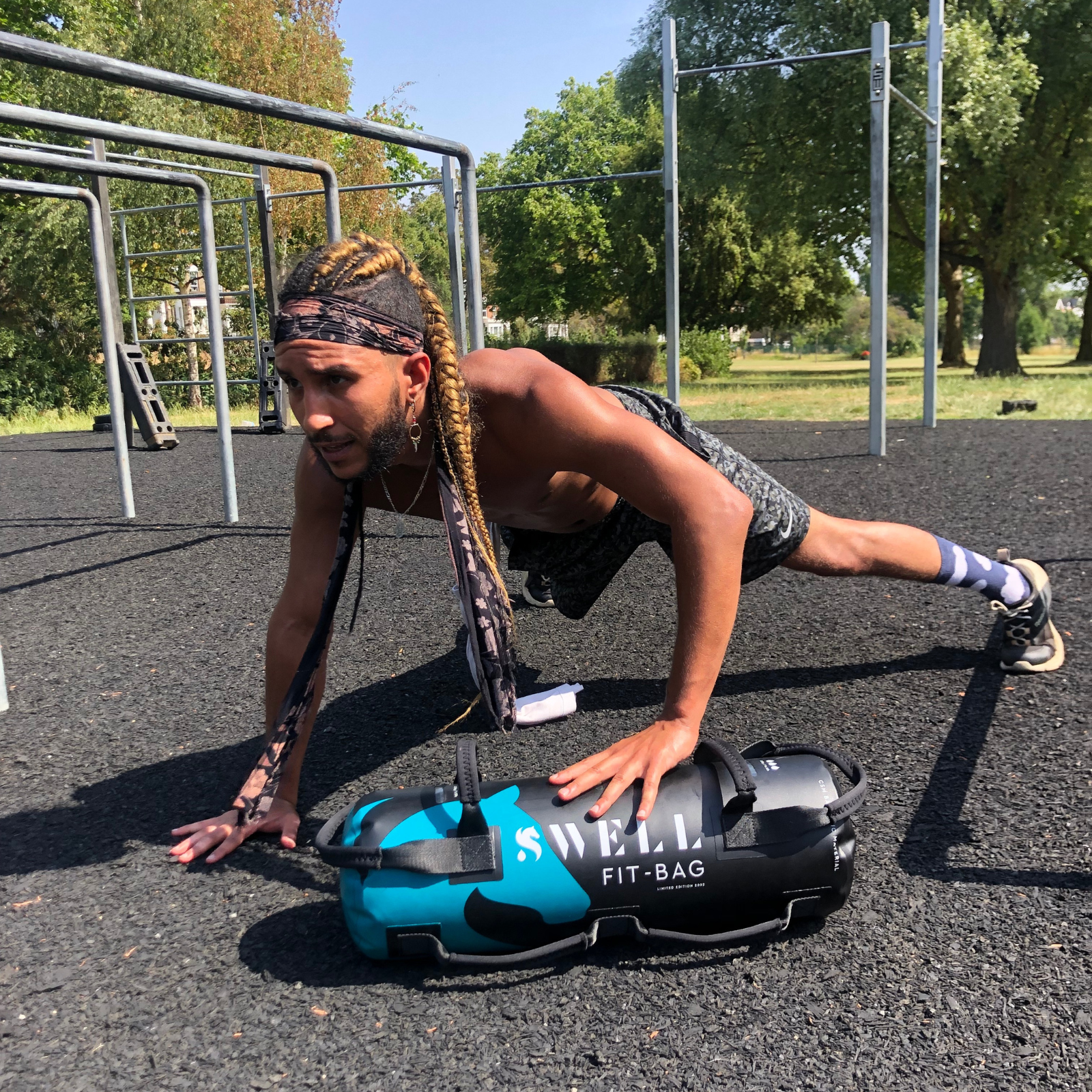 A man doing press-ups in a calisthenics park on the swell fit bag, a water weighted mobile gym equipment.